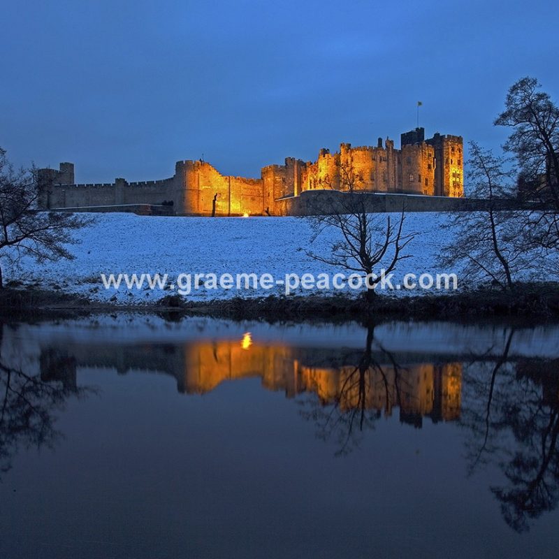 Alnwick Castle in winter floodlight at dusk, Alnwick, Northumberland
