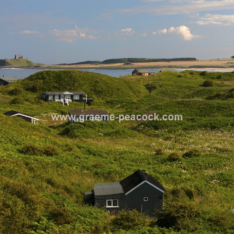 Beach bungalows on Embleton Links overlooking Dunstanburgh Castle near Embleton, Northumberland