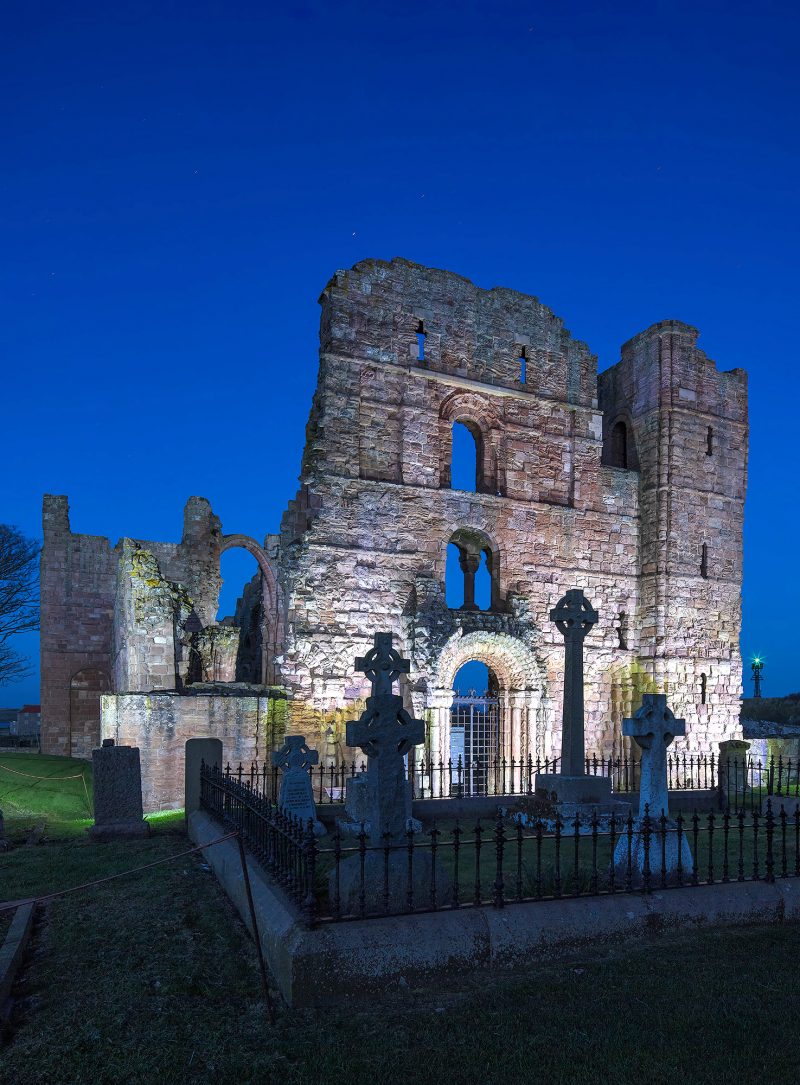 Lindisfarne Priory floodlit at dusk, Holy Island, Northumberland, England, UK